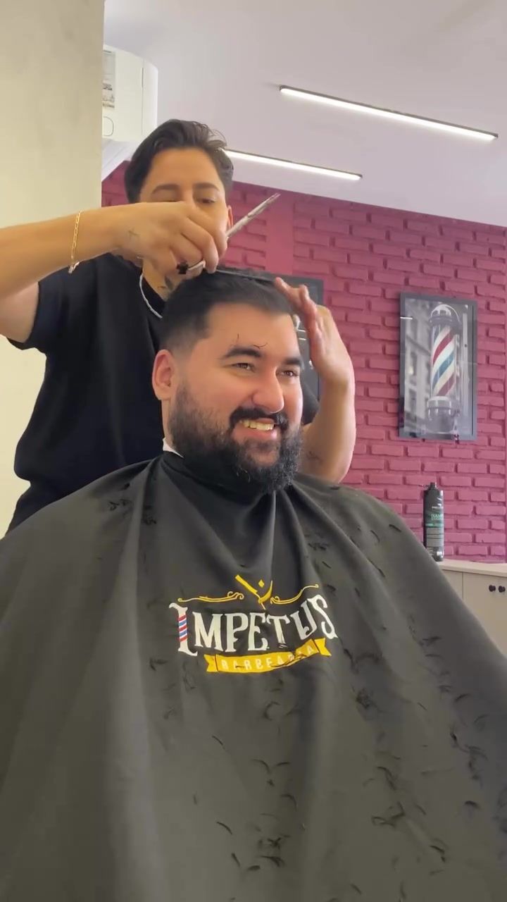 Cliente sorrindo, com a capa da Impetus, durante o corte